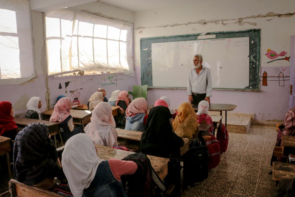 A teacher and a class of girls and women in a classroom in northwest Syria